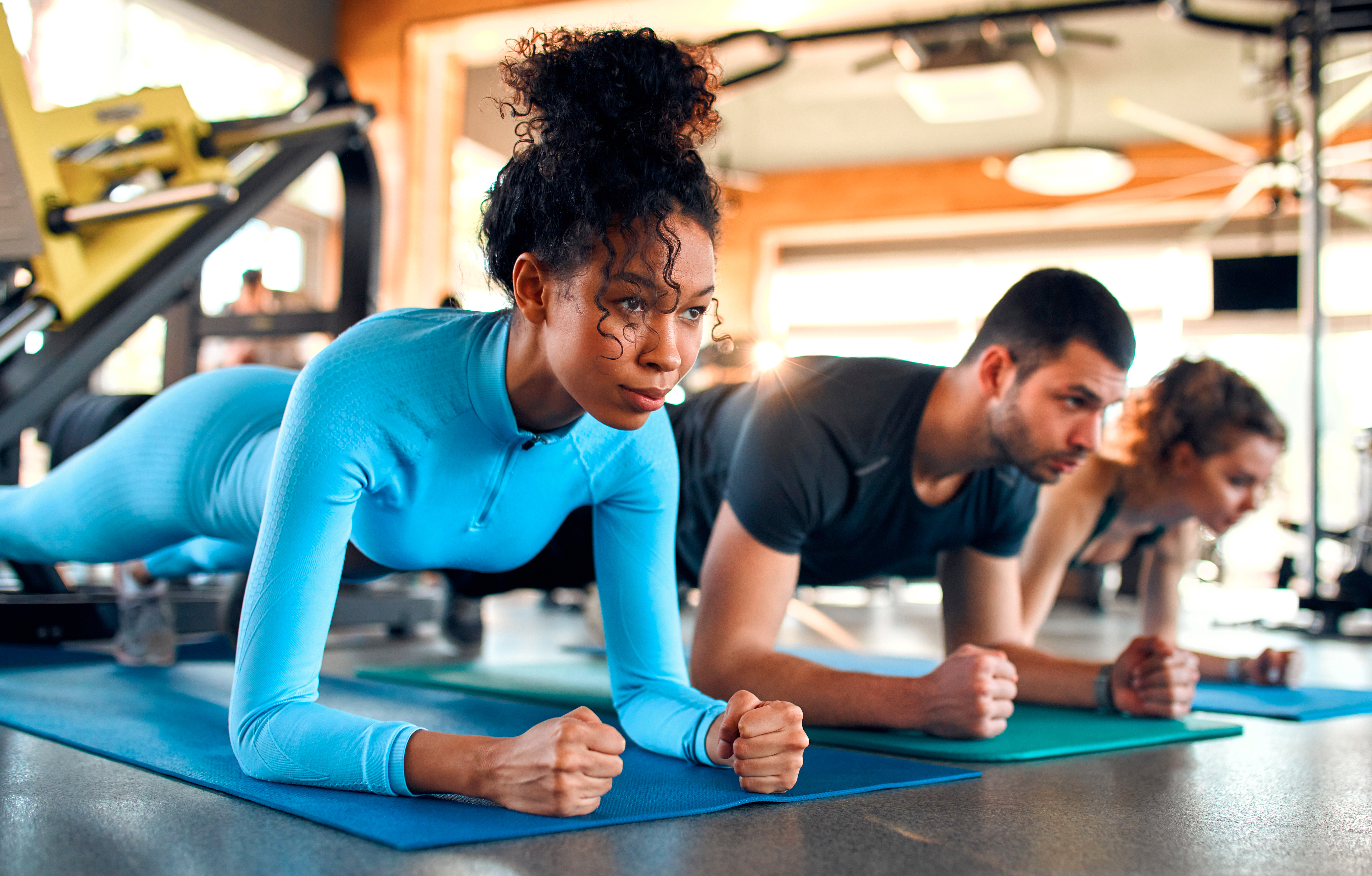 Slim women and muscular man in sportswear doing plank exercise on rubber mat in gym club. The concept of sports and recreation.