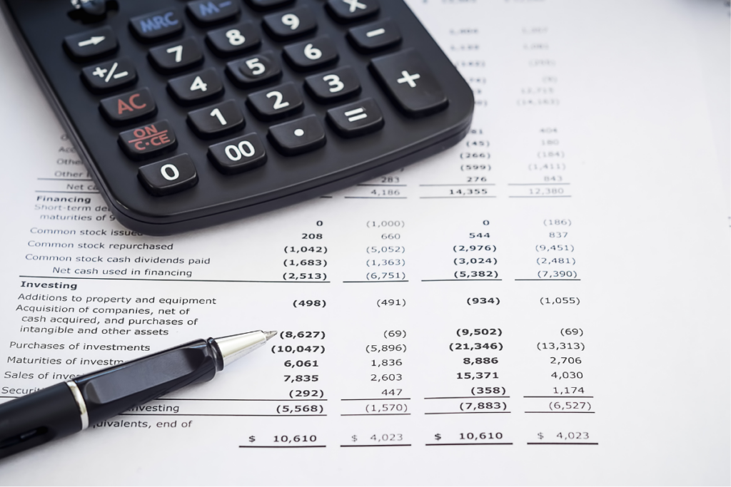 calculator and pen on top of a business expenditure statement